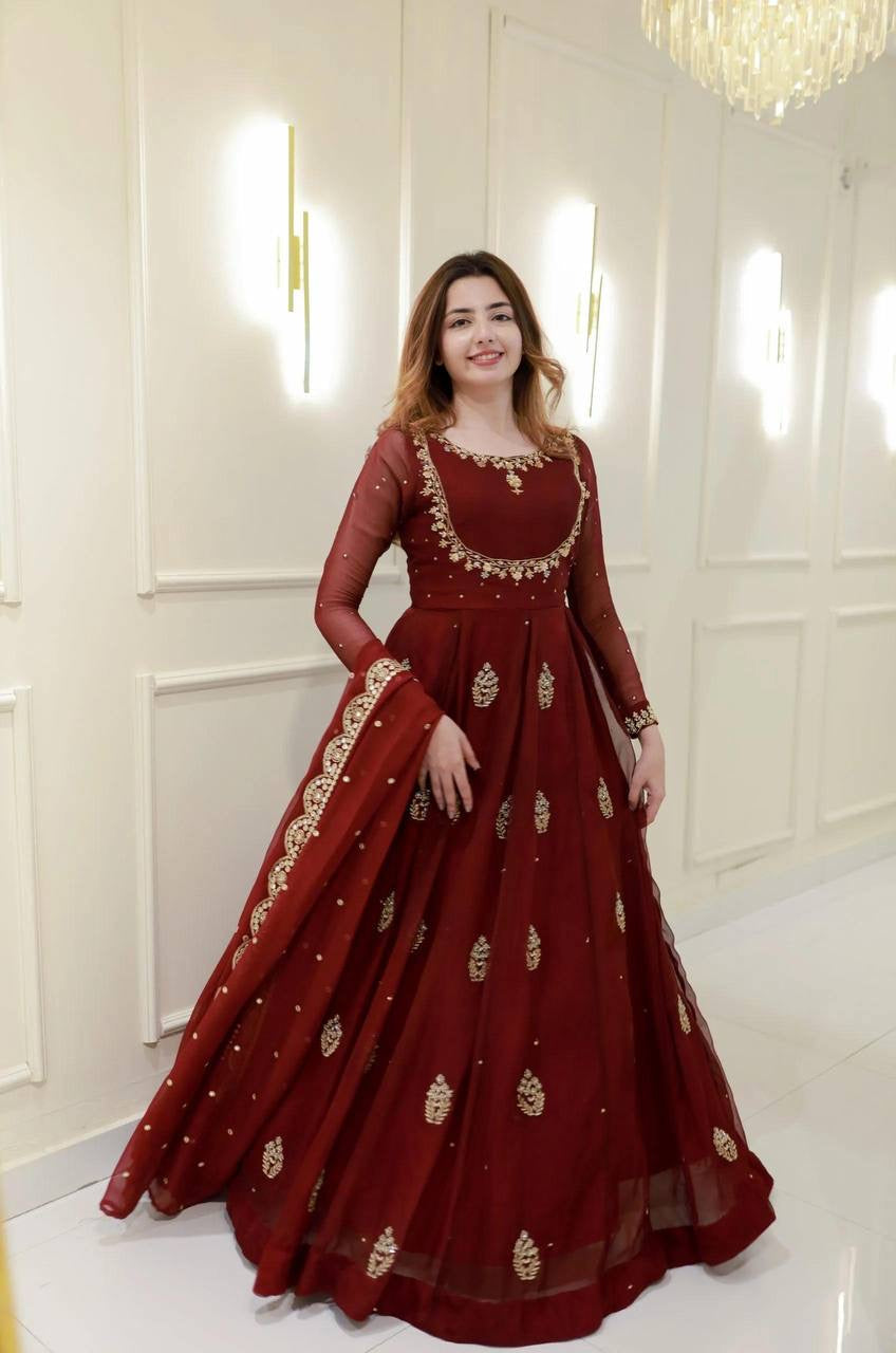 Woman wearing a red embroidered dress in a white room