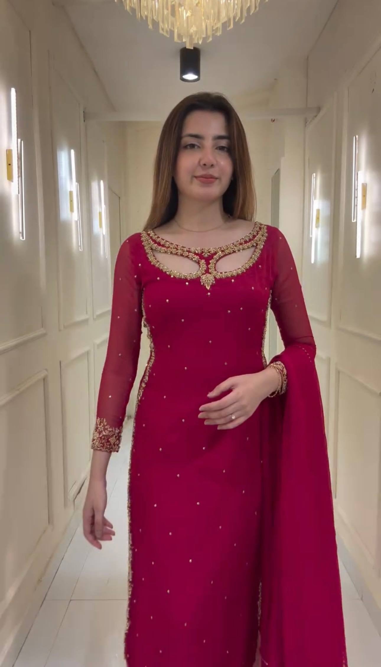 Woman in a red traditional outfit standing in a well-lit hallway.