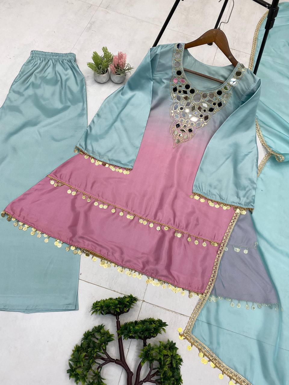 Colorful traditional outfit with a pink and blue top and matching skirt on a white background.