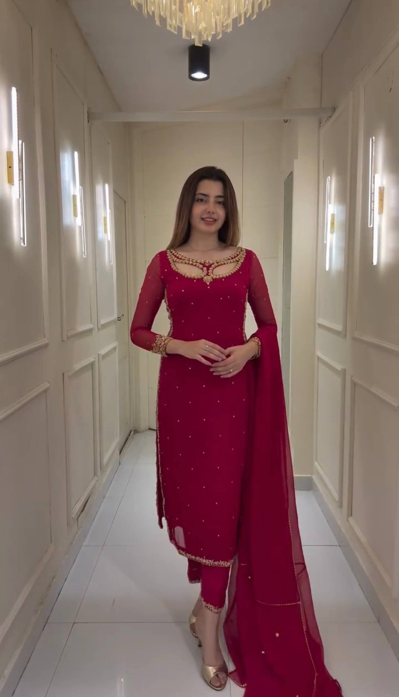 Woman in a red traditional outfit standing in a well-lit hallway.