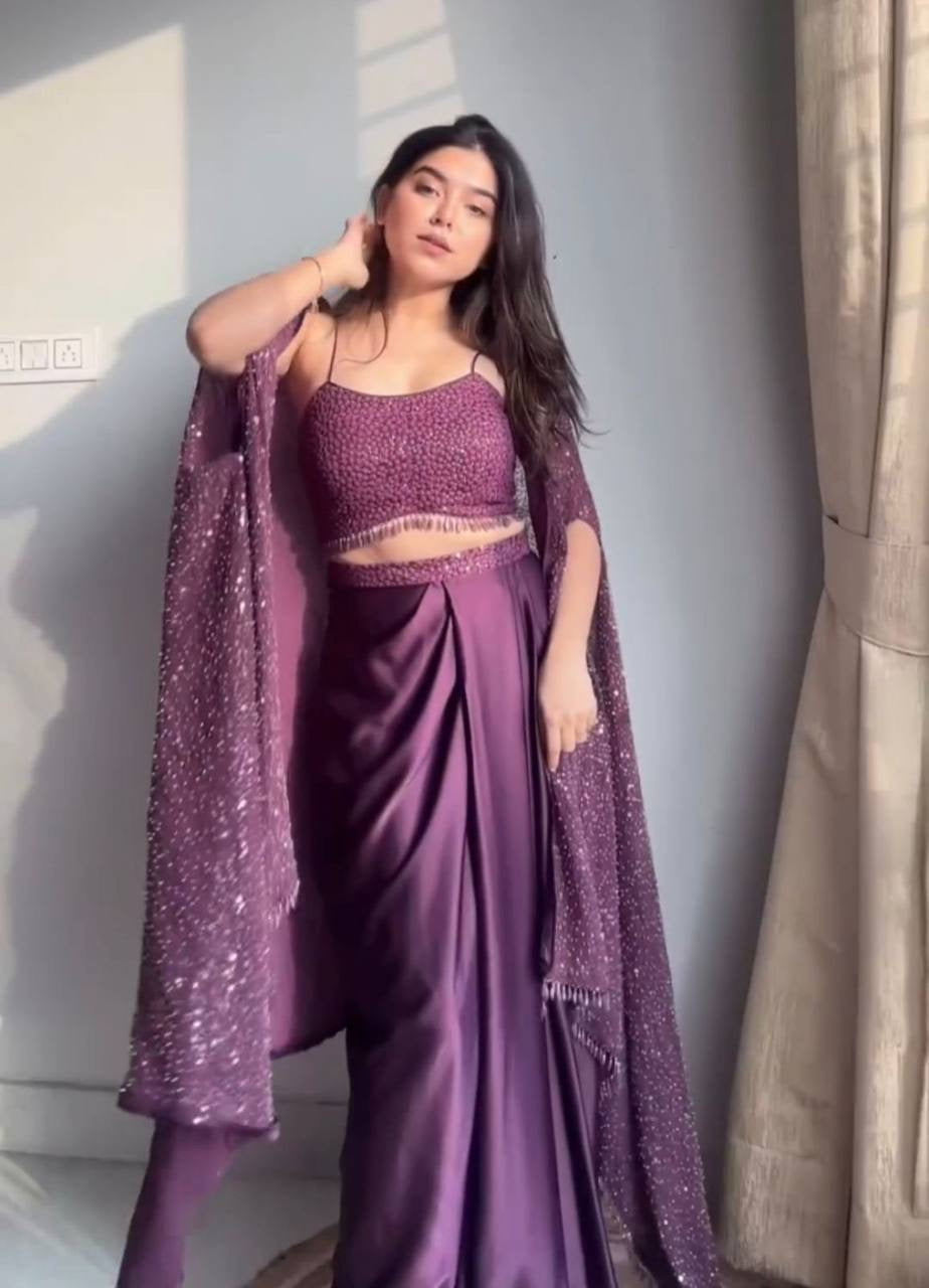 Woman wearing a purple saree with a matching blouse against a neutral background