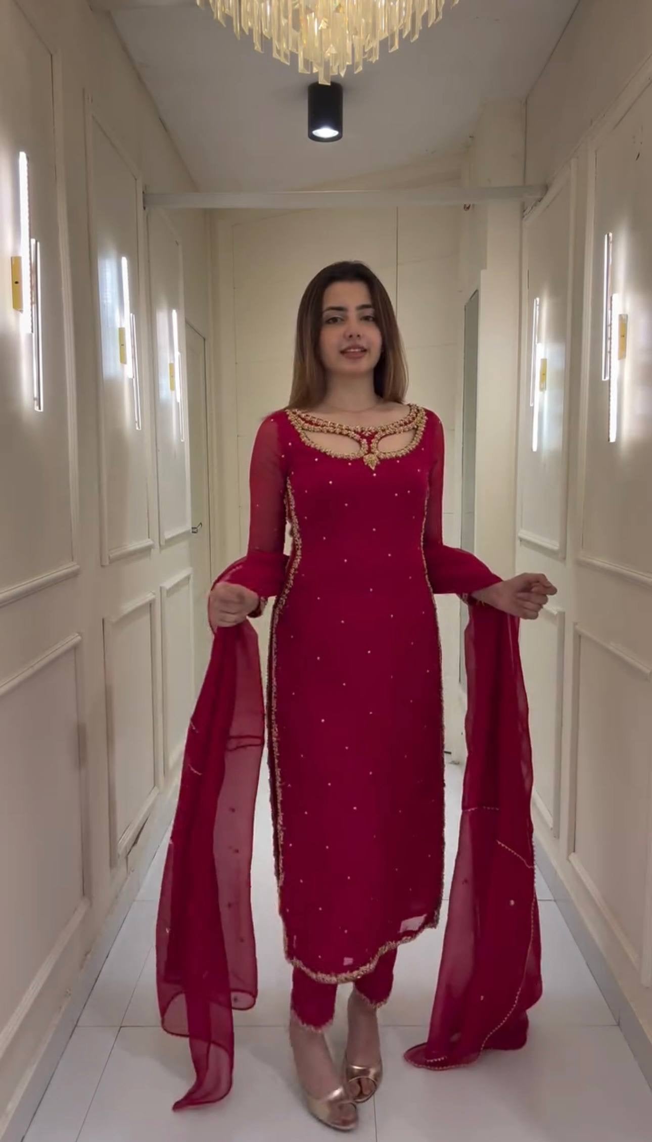 Woman in a red traditional outfit standing in a well-lit hallway.