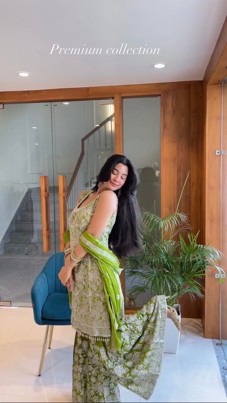 Woman in a floral dress with green accents standing indoors, with text 'Premium collection' above.