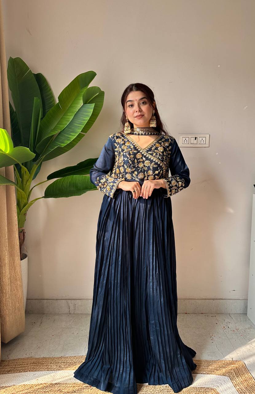 Woman in a traditional outfit standing indoors with a plant in the background