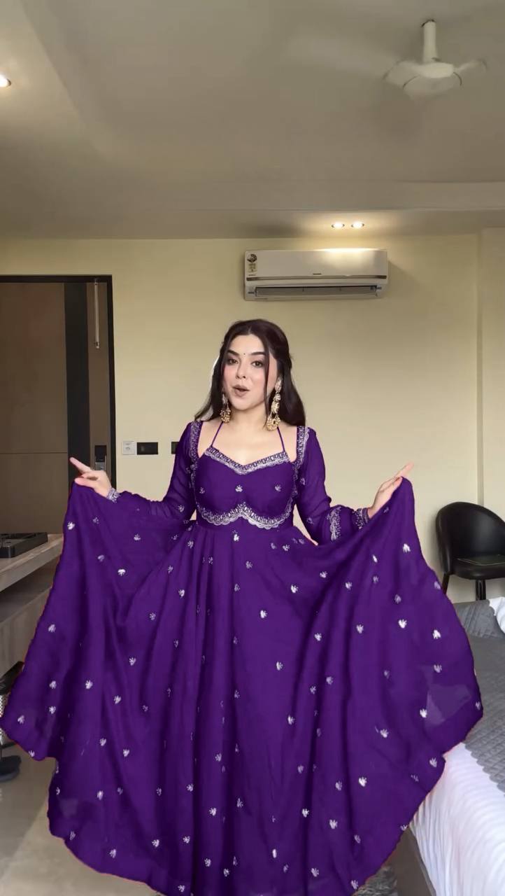 Woman wearing a purple dress with white patterns in an indoor setting.