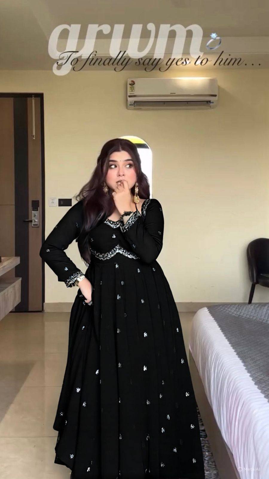 Woman in a black dress with silver details standing in a room.